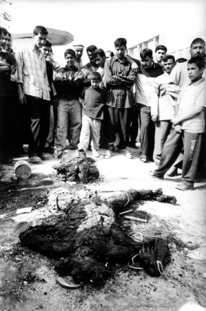 FALLUJAH, IRAQ - MARCH 31: An Iraqi mob gather around a mutilated corpse following an attack on two civilian vehicles on March 31, 2004 in Fallujah, Iraq. Local residents vented their anger by throwing stones at the burning vehicles and dragged out the mutilated bodies. The incident followed an other attack in the town earlier in the day on a U.S. military convoy that killed 5 American soldiers. PHOTOGRAPH BY STANLEY GREENE--AGENCE VU